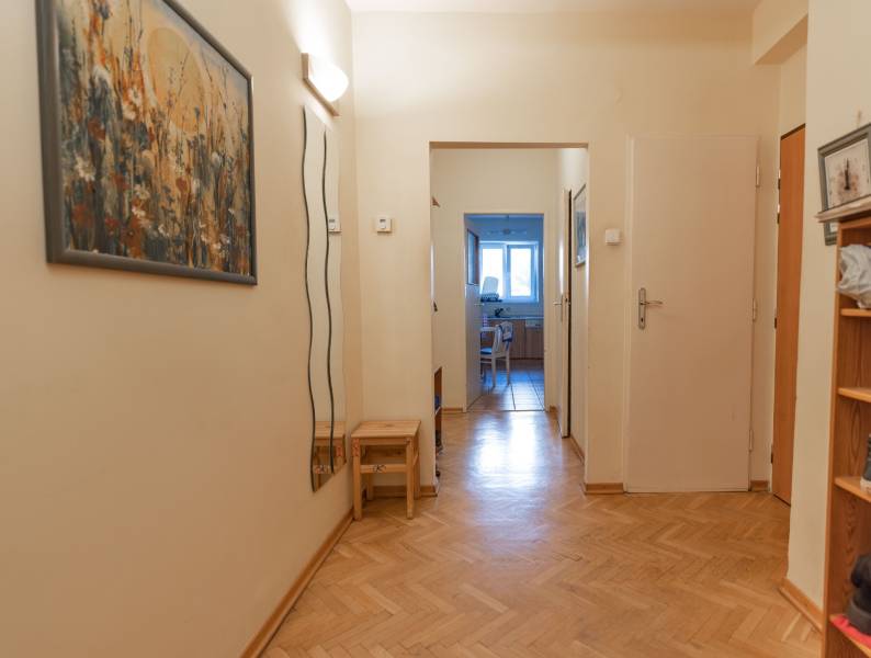A hallway in a 4-room apartment with laminate flooring and a picture on the wall.