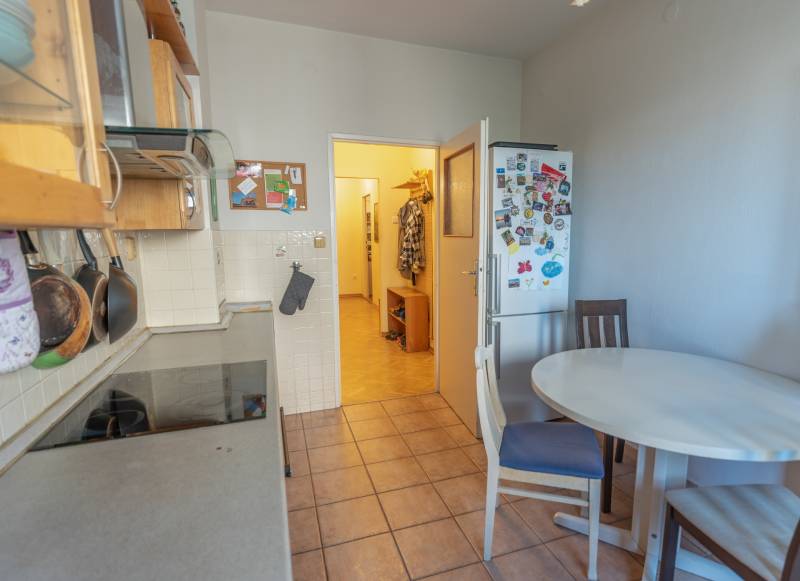 A kitchen in a 4-room apartment with a table, chairs, a refrigerator, and a stove.