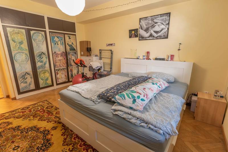 Bedroom in a 4-room apartment with a large bed, decorative pictures, and a wooden decor floor.