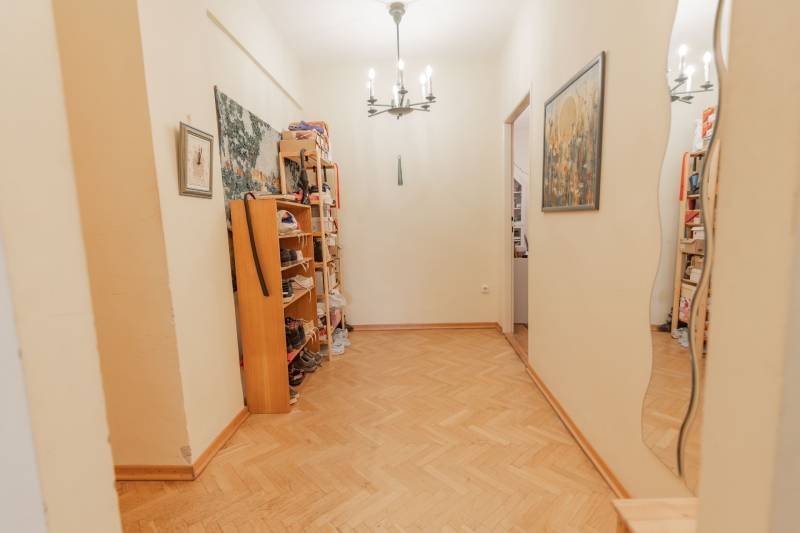 A hallway in a 4-room apartment with shoe shelves and a wooden decor floor.