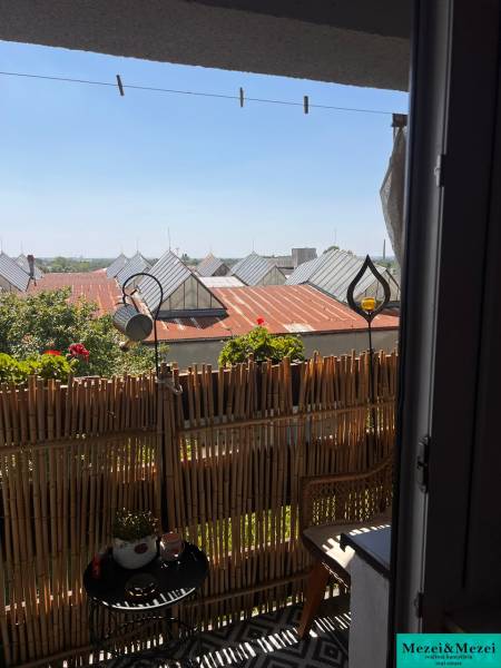 A balcony in a 3-room apartment with rattan furniture and a view of the rooftops.