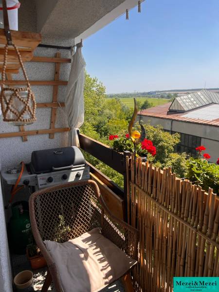 A balcony of a 3-room apartment with seating, a grill, and a view of greenery in Pezinok.