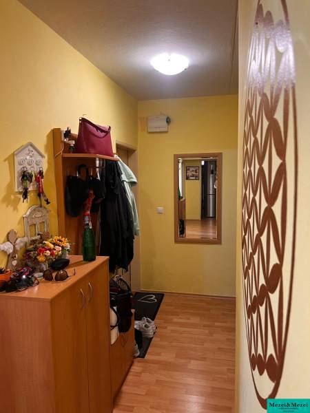 A hallway in a 3-room apartment with a wardrobe, a coat rack, and a mirror, the walls are yellow.