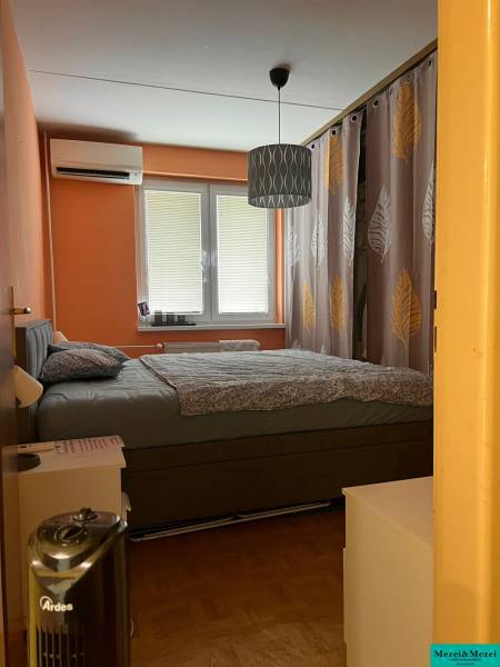 Bedroom in a 3-room apartment with a double bed, orange walls, and air conditioning.