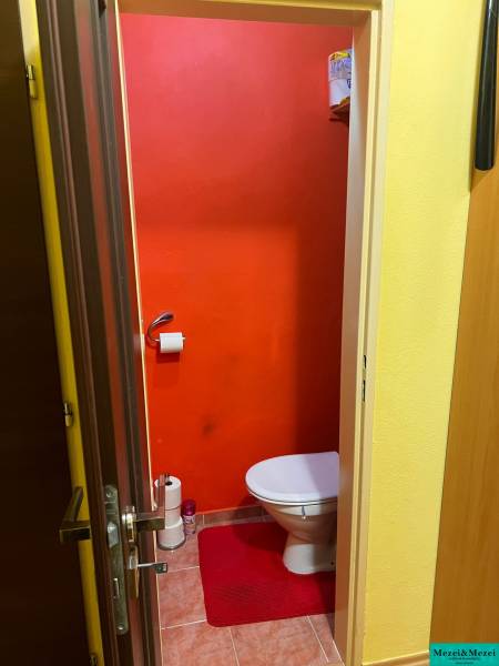 A bathroom with light orange walls and a red rug, 3-room apartment.