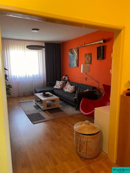 Living room of a 3-room apartment with an orange wall, a sofa, and a coffee table.