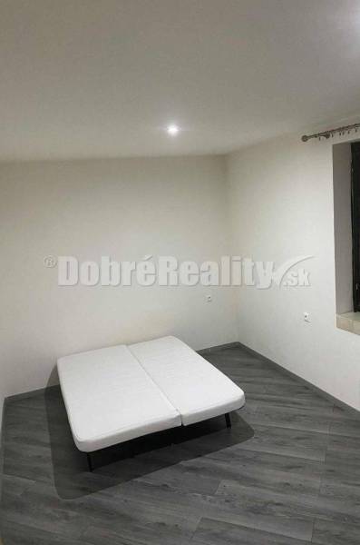 Bright room, dark wood floor, simple white mattress. Family house.