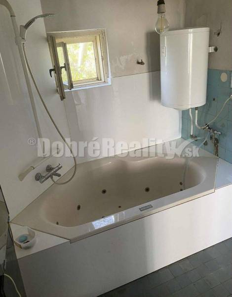 A bathroom in a family house with a bathtub, shower, and water heater.