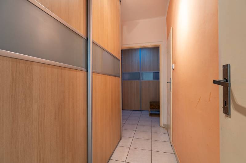Hallway in a one-room apartment with a built-in wooden wardrobe and tiled floor.