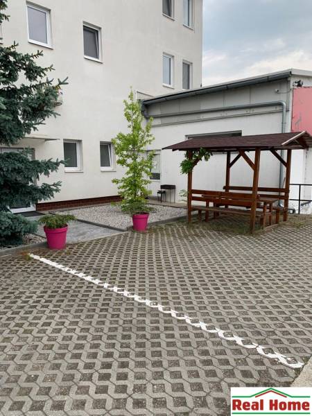 Mansion with paving, wooden seating, and plants in pink pots on Šamorínska Street.