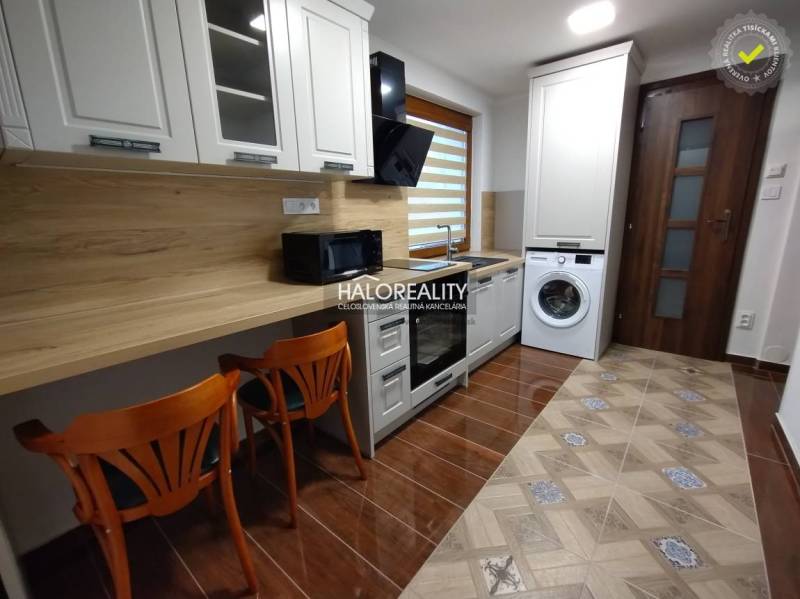Studio apartment with a kitchenette, washing machine, and wooden chairs.