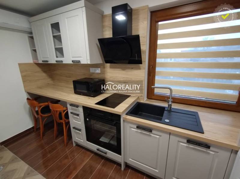 A kitchen in a studio apartment with wooden elements, equipped with an oven, sink, and appliances.
