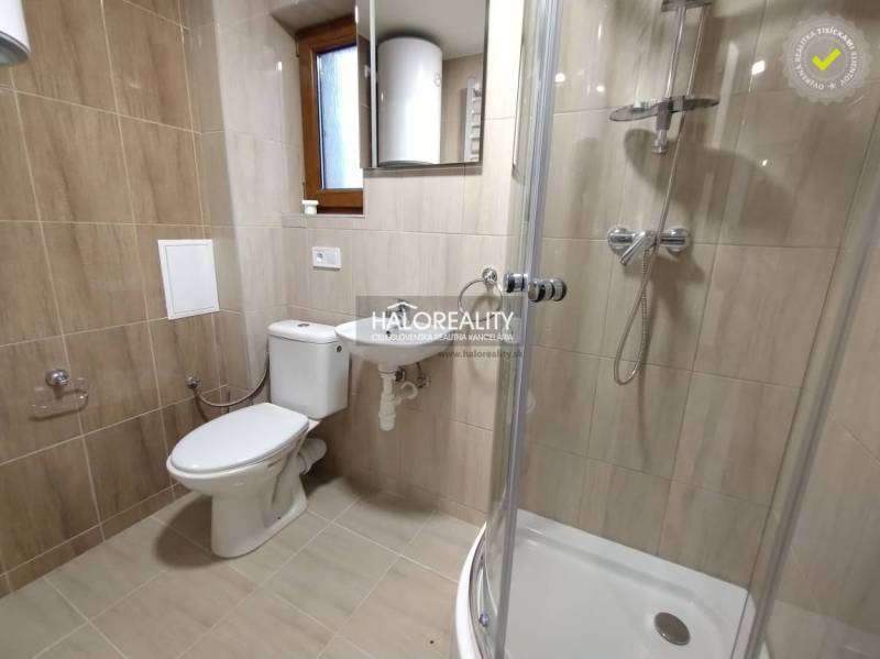 A bathroom in a studio apartment with a toilet, sink, shower, and window.