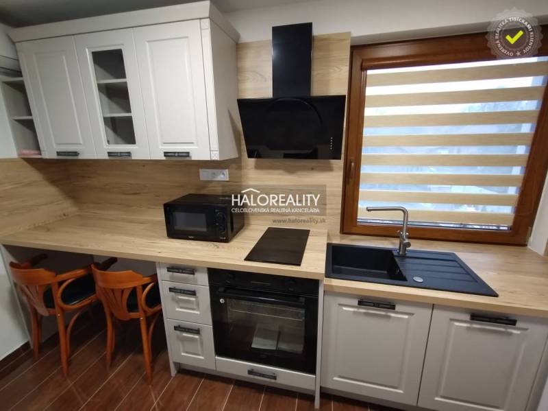 Kitchen area in a studio apartment with wooden furniture and appliances.