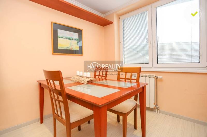 Dining room in a 2-room apartment with a wooden table and chairs, painting on the wall.