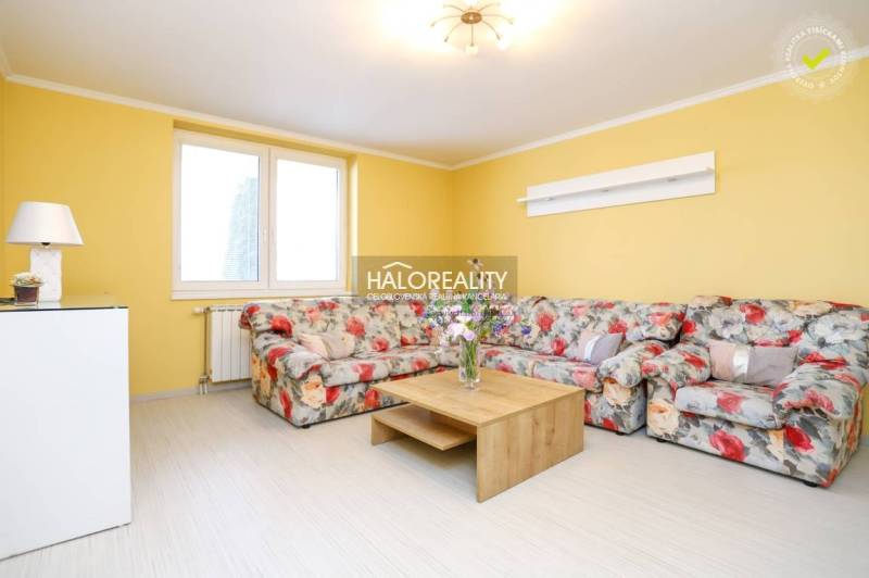 Yellow living room with a floral sofa and a wooden coffee table in a two-room apartment.