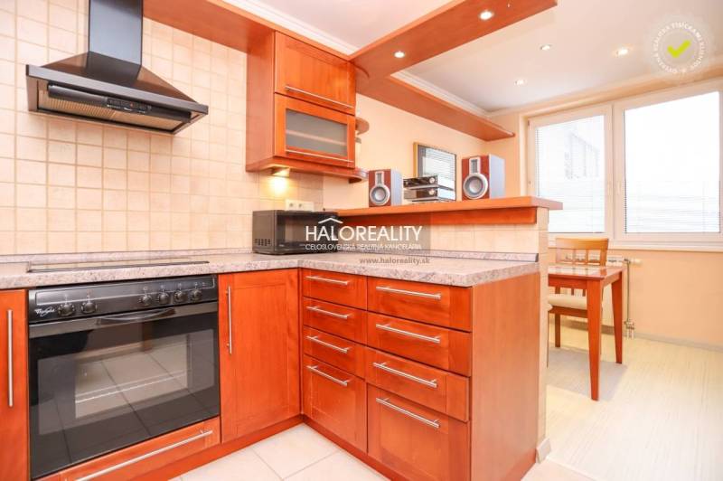 A kitchen in a 2-room apartment with a wooden kitchen unit, stove, extractor hood, and dining area.