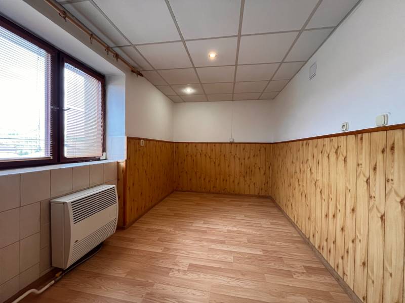 A room with wooden paneling, laminate flooring, and a window in a 2-room apartment.