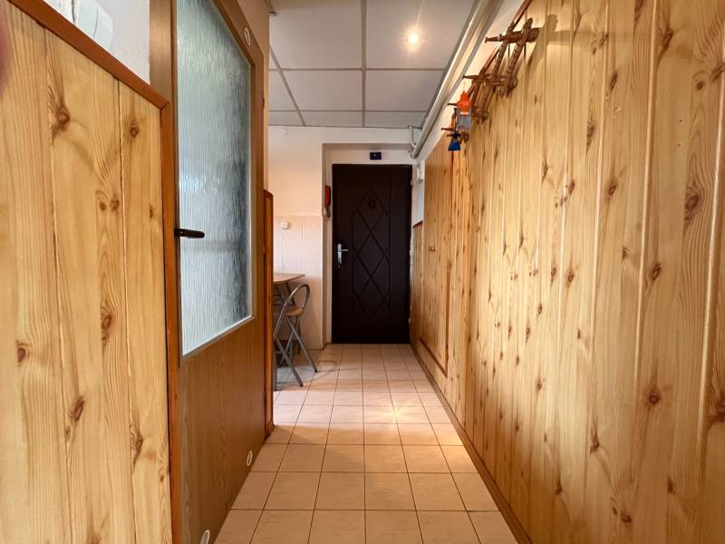 Wooden paneling in the hallway of a 2-room apartment, light tiles, folding chairs.