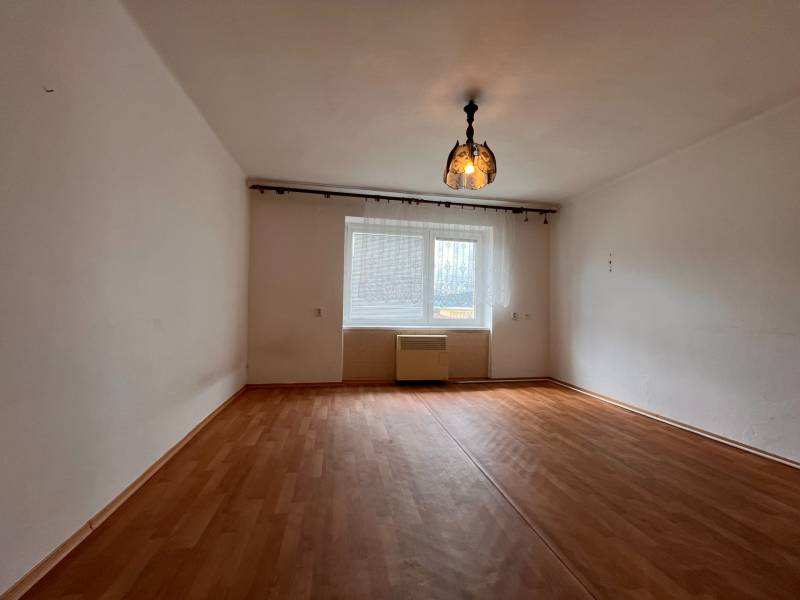 A room with a wooden floor and pendant lighting in a 2-room apartment.
