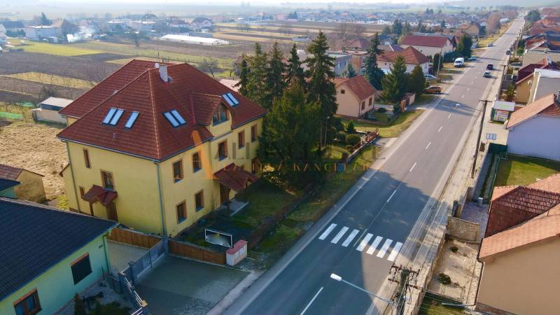 A building on Chrabrany Street in Topoľčany, surrounded by houses and trees, by the main road.