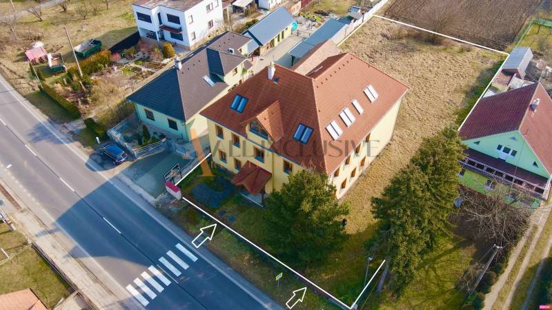 The building on Chrabrany Street in Topoľčany, surrounded by houses and greenery.