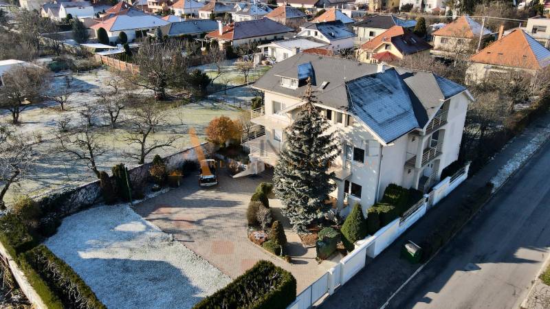 A villa on Sportsmen Street in Topoľčany, surrounded by greenery and a white fence.