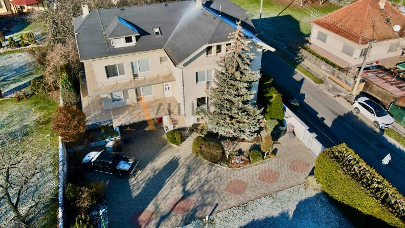 A villa on Športovcov in Topoľčany with two cars and a large garden.