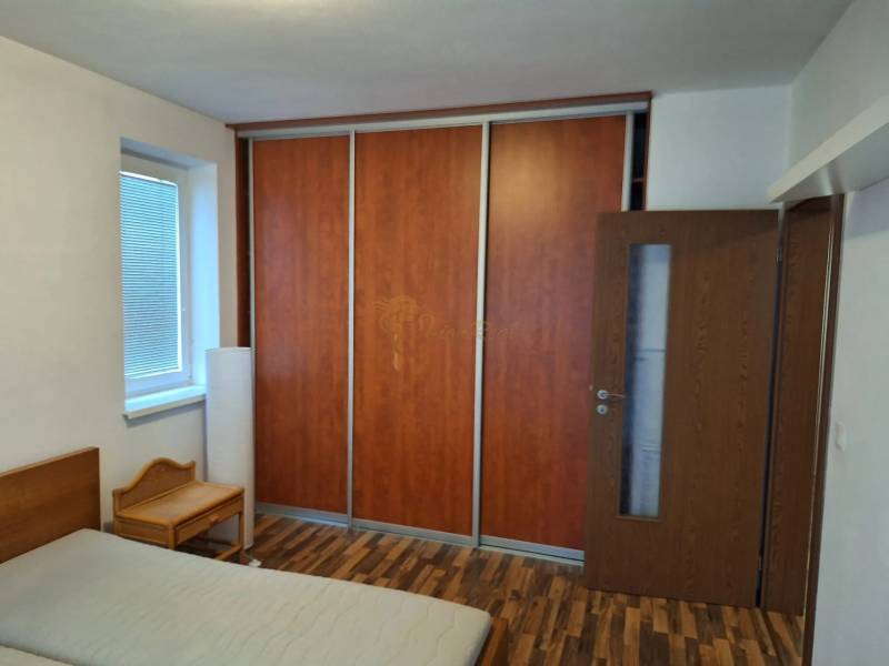Bedroom in a 2-room apartment with wooden flooring, a wardrobe, and a bed.