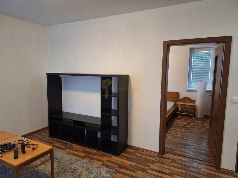 Wooden floor, black shelf, entrance to the bedroom in a 2-room apartment.