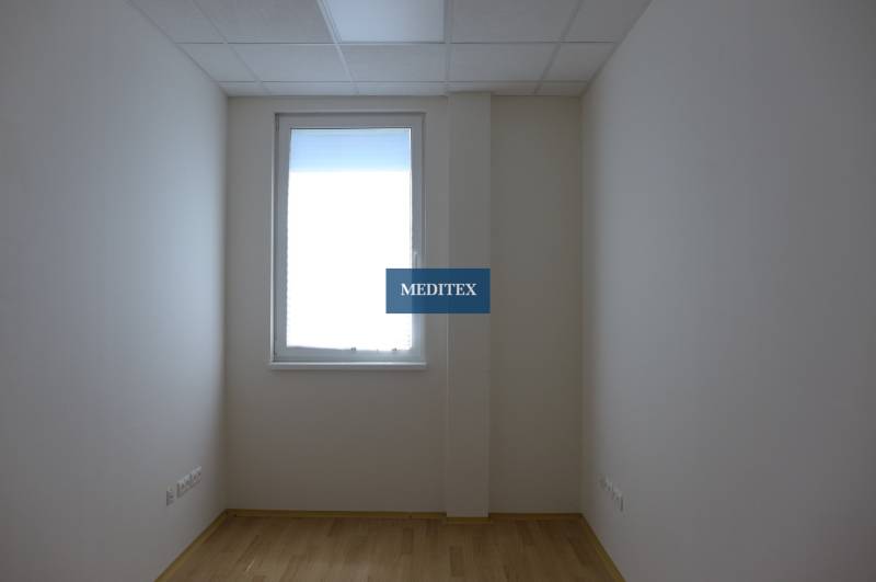Room with a window, light walls, and floor in warehouse and hall spaces.