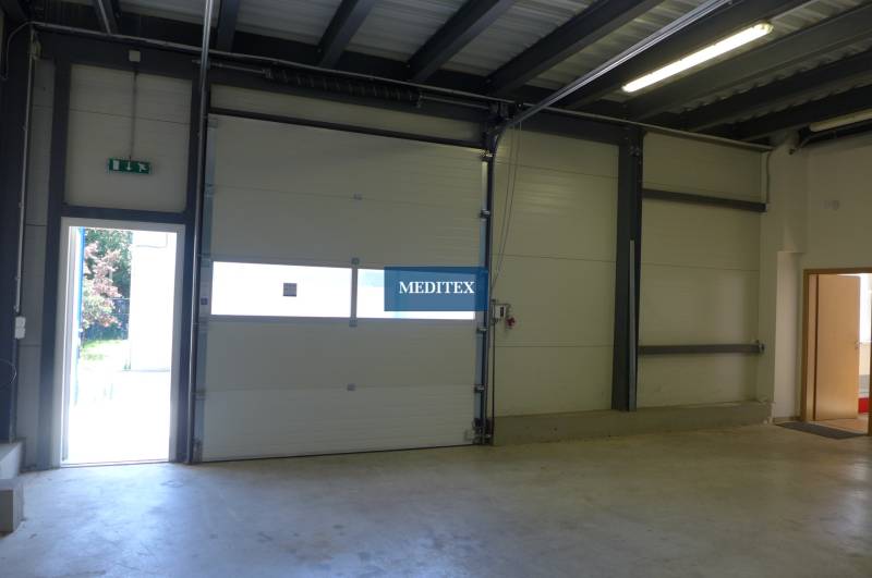 Interior of a warehouse with large garage doors and lighting. Warehouses and halls.