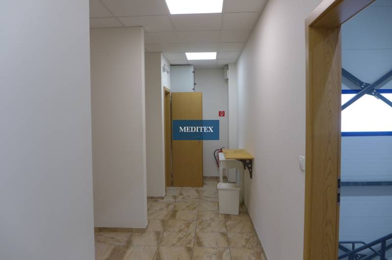 A narrow interior corridor with multiple doors, a chair, and a trash can. Warehouses and halls.