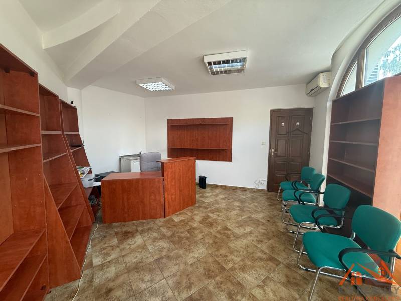 Offices with wooden furniture and green chairs, tiles, arched window.