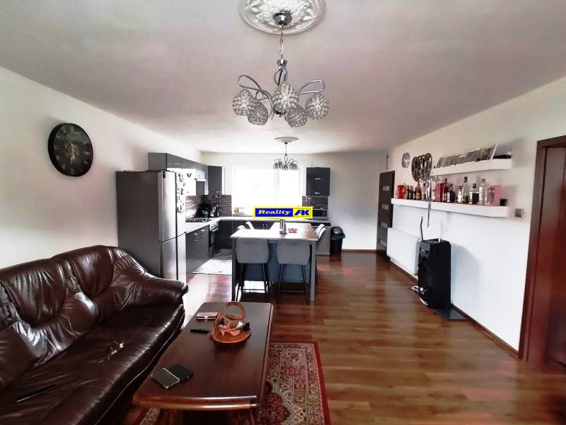 Living room and kitchen in a family house with a sofa, table, and shelves.