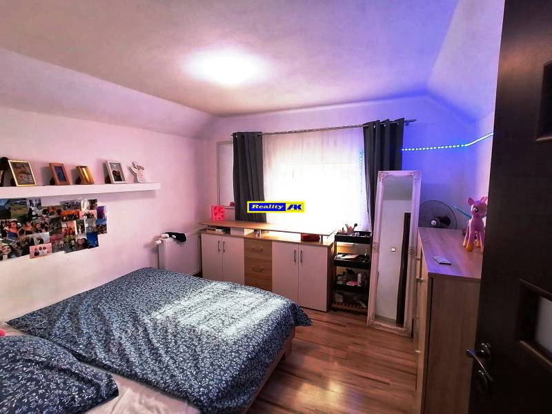 Bedroom in a family house with wooden flooring, decorations, and storage space.