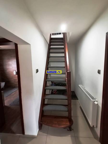 Interior of a family house with a staircase, next to a radiator and entrance to the bathroom.