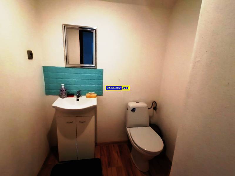 A toilet in a family house with a sink, a mirror, and blue tiles.