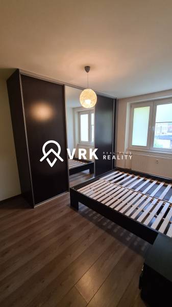 Bedroom in a 2-room apartment with a dark wardrobe, bed, and window.