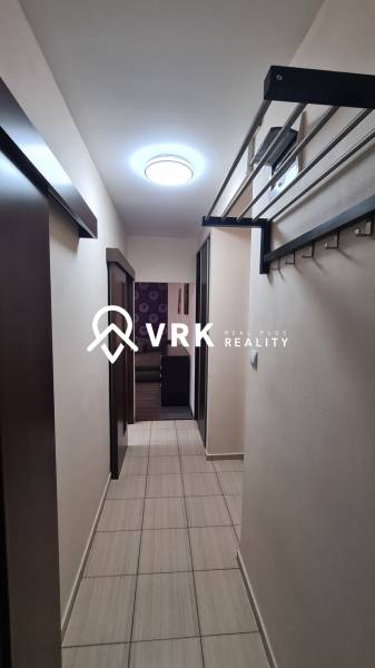 A narrow hallway in a 2-room apartment with ceramic tiles and a fold-out coat rack system.
