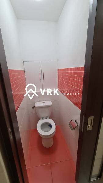 A bathroom with white tiles and a cabinet in a 2-room apartment with red tiles.