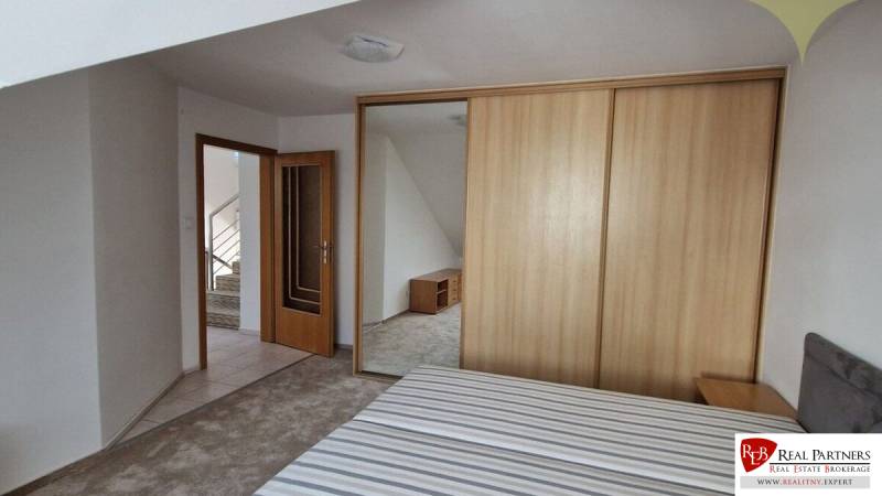Bedroom in a family house with a wooden wardrobe and open doors to the hallway.