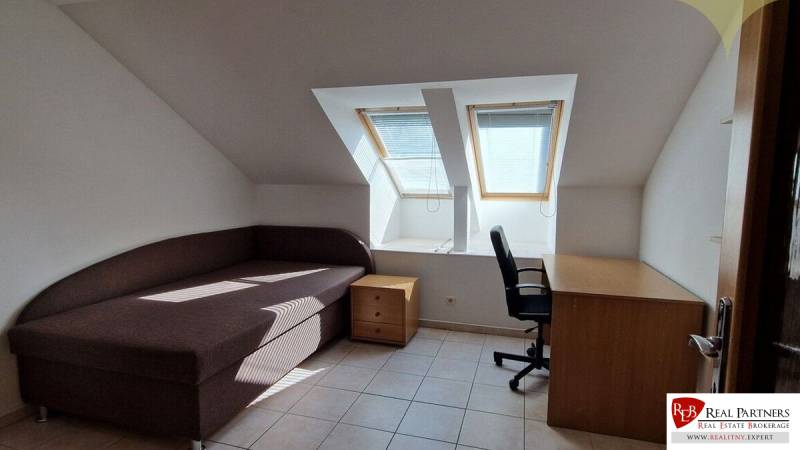 Attic room in a family house with a sofa bed, a coffee table, and a desk.
