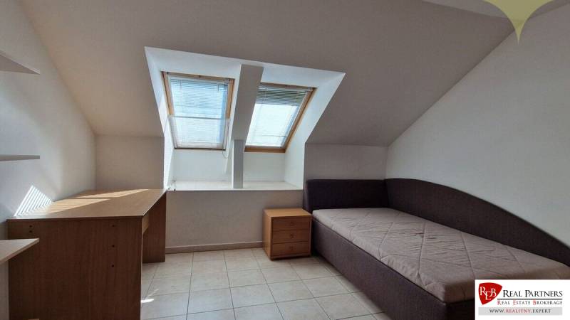 Attic room in a family house with two skylights, a bed, and a desk.