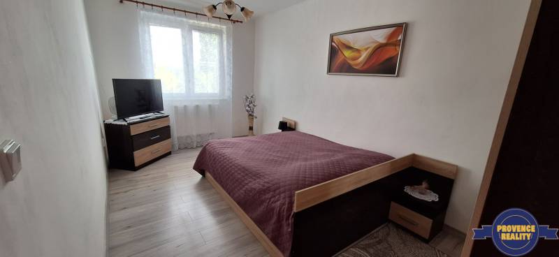 A bedroom in a 3-room apartment with a bed, television, and wall decoration.