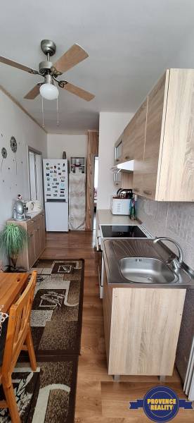 A kitchen in a 3-room apartment with wooden furniture and a ceiling fan.