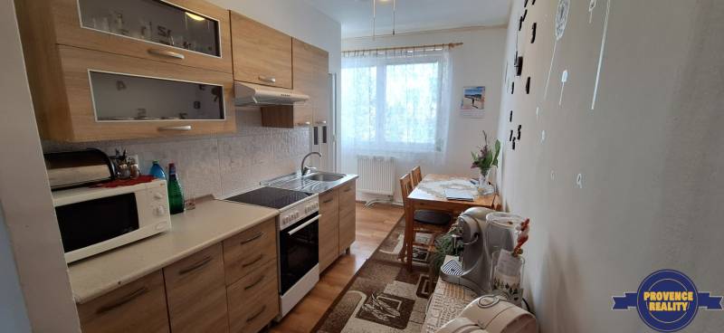 A kitchen in a 3-room apartment with wooden cabinets and a dining table, light decoration.