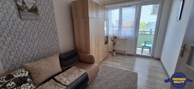 A room in a 3-room apartment with a sofa, wardrobe, and balcony.