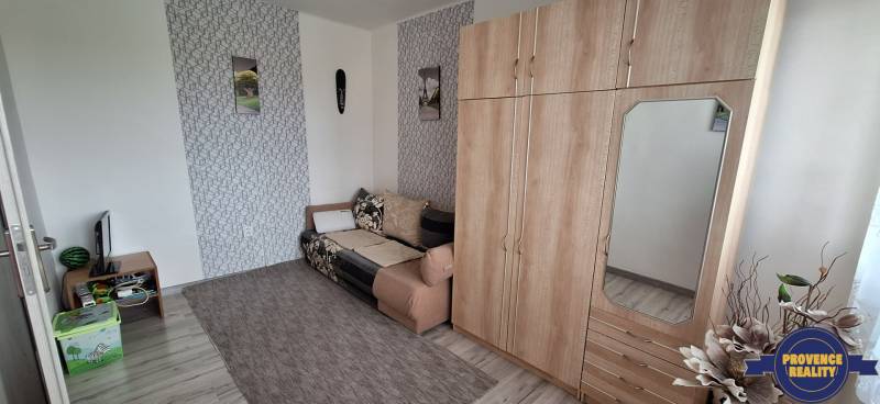 Living room in a 3-room apartment with a sofa, a wardrobe, and decorations on the wall.
