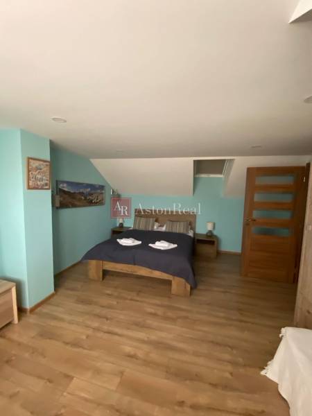 Bedroom in a family house with a double bed, wooden floor, and decorations.